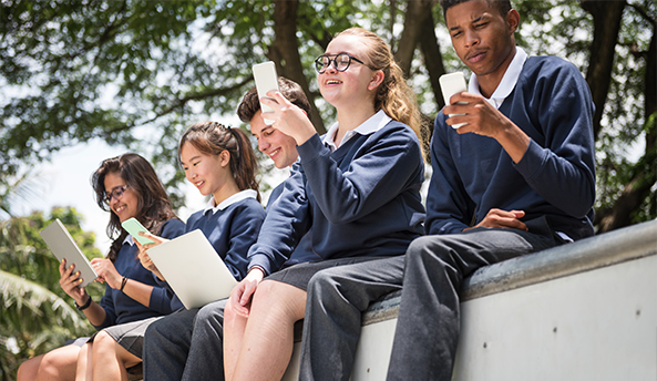 student-resources Group of five students enjoying their phones and laptops outdoors.