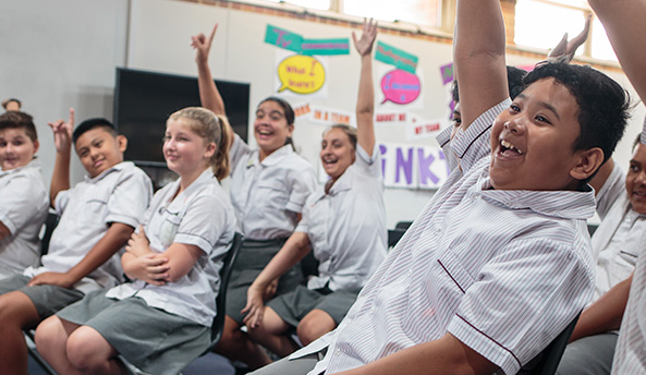 about-evaluation-report Classroom of excited and engaged students participating in an activity.
