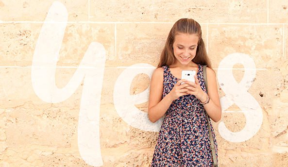 Happy young girl playing on her phone with Optus Yes logo in the background.