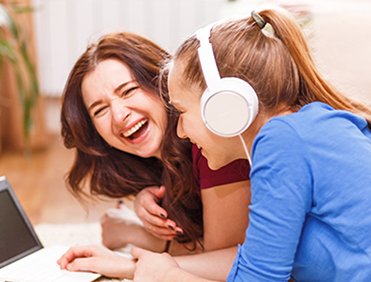 Two young women enjoying an activity on a laptop together outdoors.