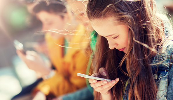 Group of three students enjoying their digital devices outdoors.