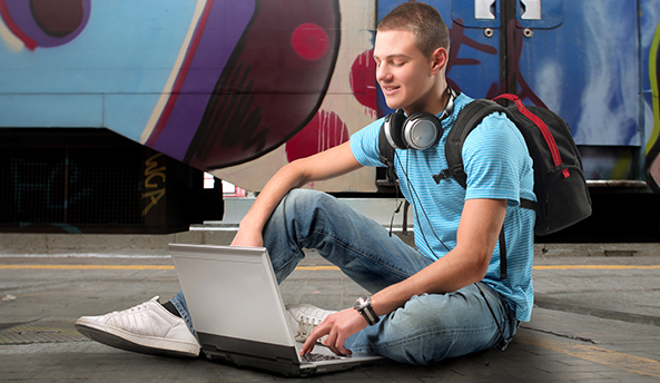 Young man sitting down and contently working on his laptop.