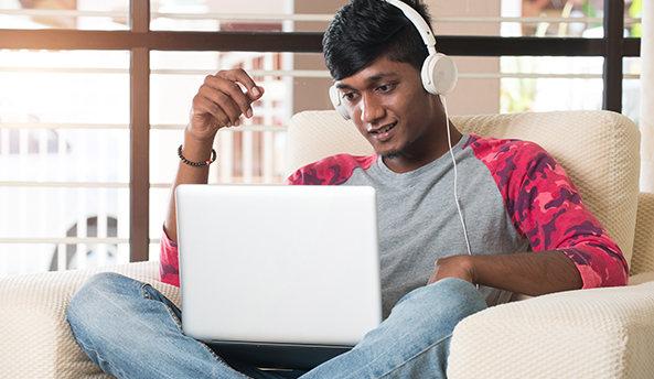 Young man comfortably sitting on a chair working on his laptop.