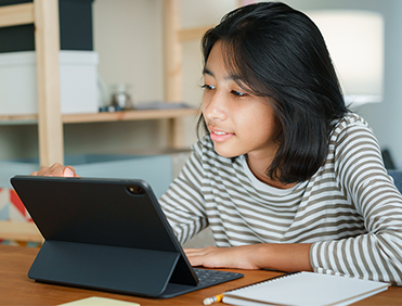 Young girl smiling at what she is watching on her iPad.