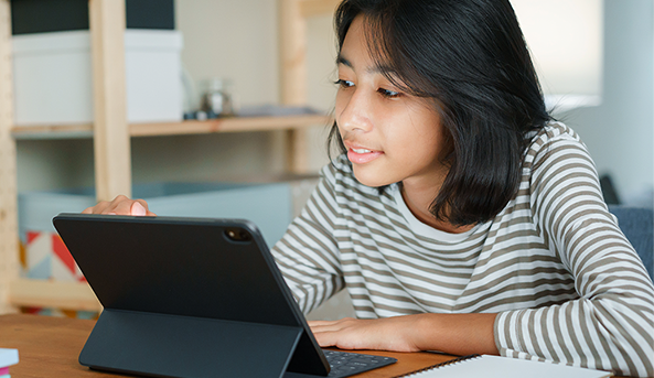593x343 Young girl smiling at what she is watching on her iPad.
