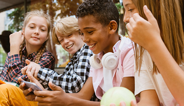 Digital_balance_tweens_Thumbnail-593x343 Group of four young friends smiling and laughing at what they are watching on a mobile phone