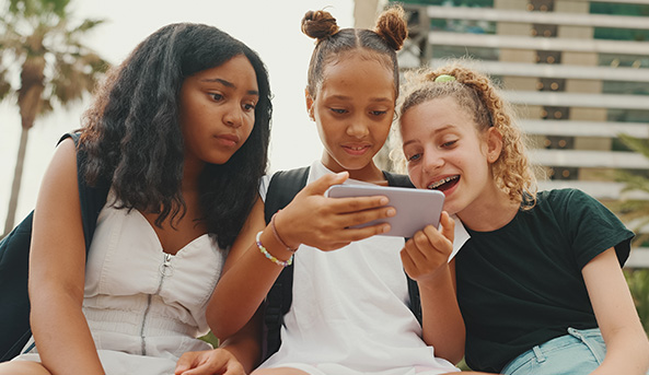 Hackers-scammers-fake-friends_tweens_Thumbnail-593x343 Young girls smiling at what they are watching on a mobile phone