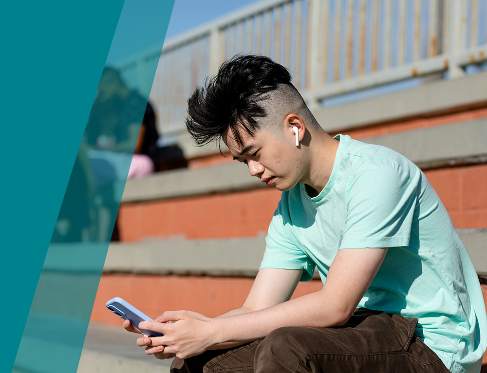 Teen boy using smartphone alone away from friends Teen boy using smartphone alone away from friends