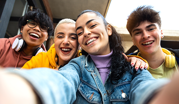 Group of four young friends smiling and taking a selfie