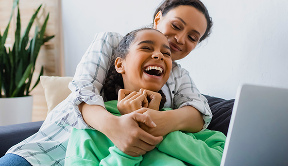 Young woman and her mother enjoying an activity on a laptop inside