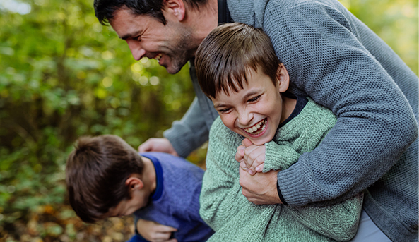 Two young boys and their dad having fun outside